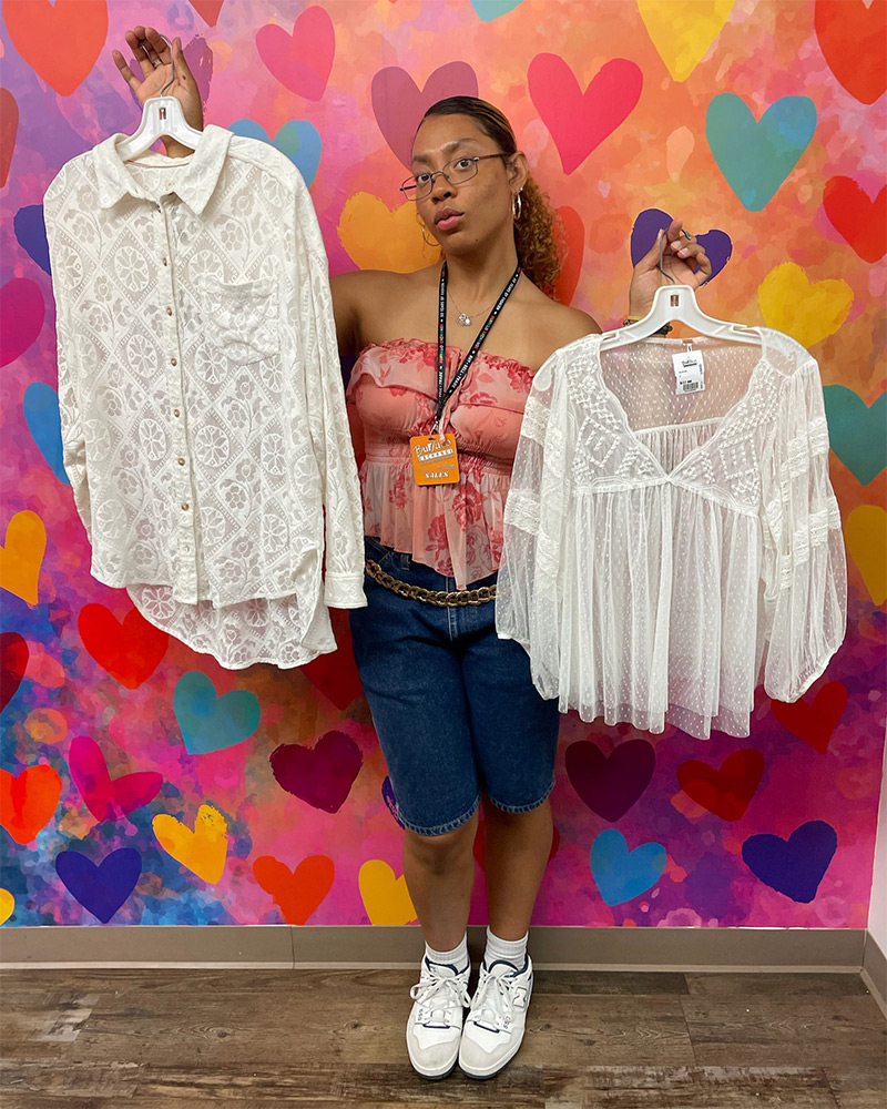 A Buffalo Exchange employee holds up two sheer white blouses 