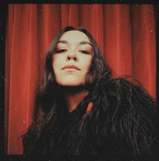 Buffalo Exchange employee Christina in front of  a red curtain