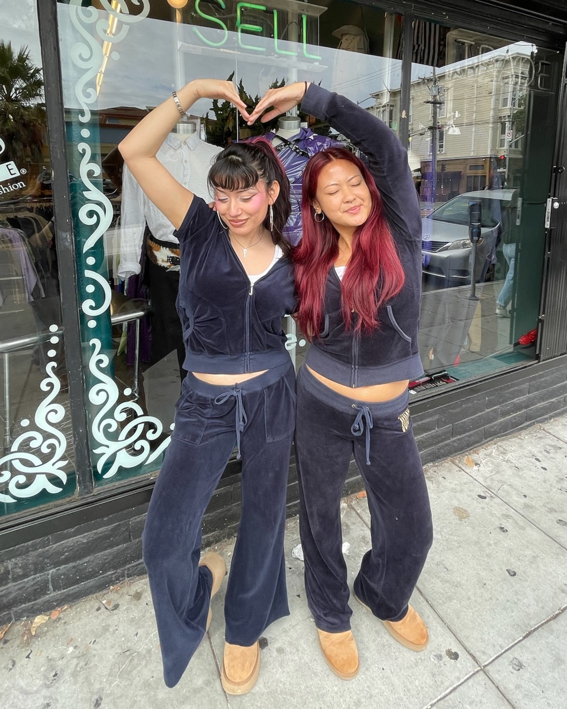 Two people in front of a Buffalo Exchange making a heart with their arms